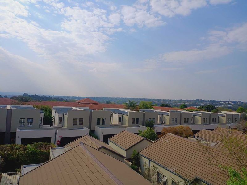 An elevated view overlooking a residential complex with modern architectural designs and tiled roofing under a clear sky.