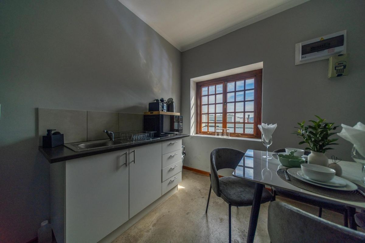 Compact kitchen area featuring built-in cabinetry, a stainless steel sink, and a wooden-framed window, providing a functional space for meal preparation.