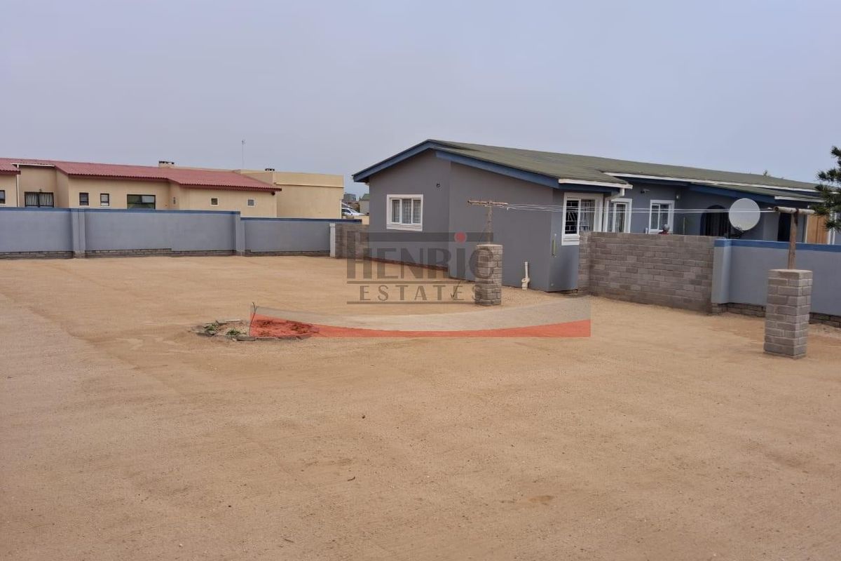 A spacious, unlandscaped rear yard featuring a perimeter wall and a clothesline, providing ample outdoor space for potential garden development.