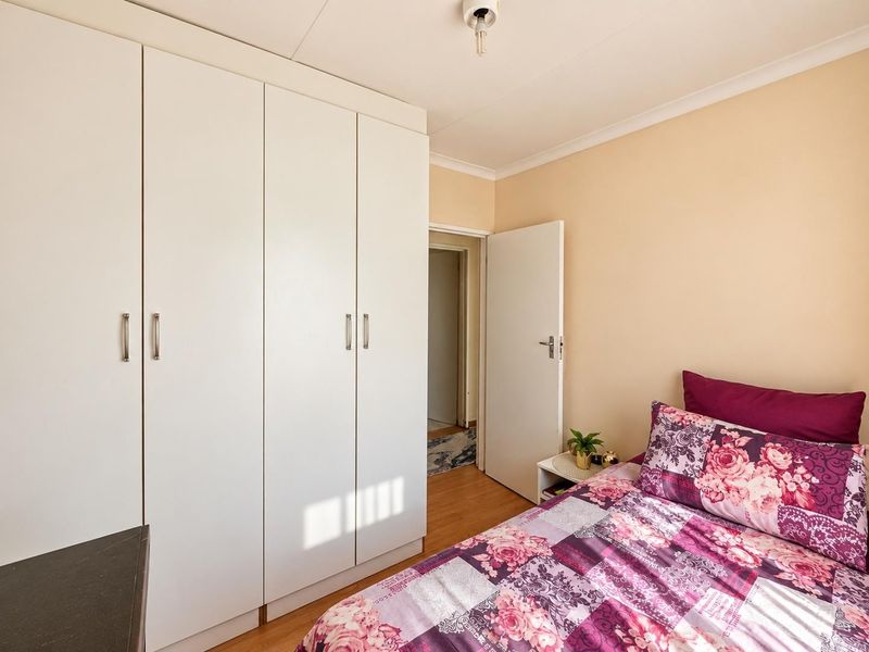 A well-maintained bedroom featuring built-in cupboards, laminate flooring, and neutral wall finishes, providing a clean and functional living space.
