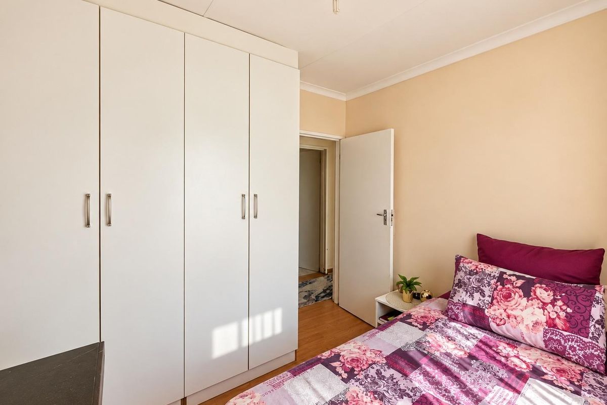 A well-maintained bedroom featuring built-in cupboards, laminate flooring, and neutral wall finishes, providing a clean and functional living space.