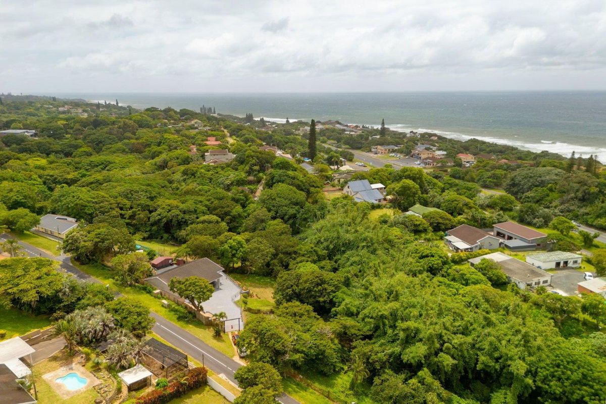 An aerial view of the coastal property and surrounding neighborhood, showcasing the lush green landscape and proximity to the ocean.