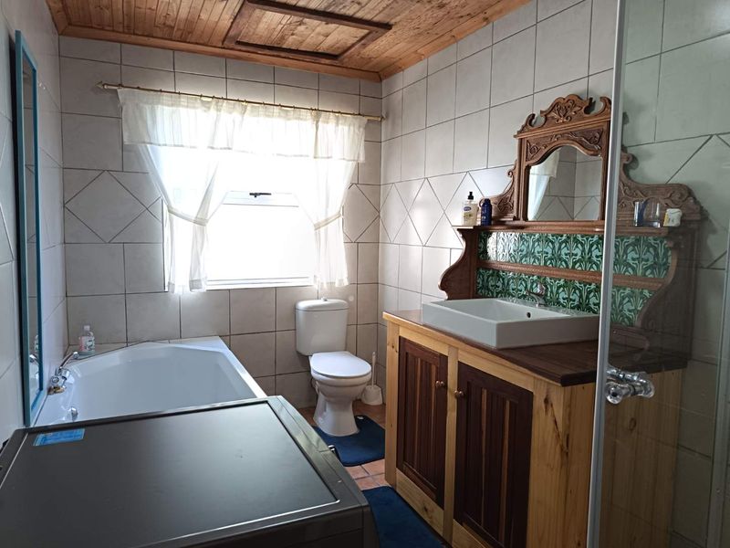 A bathroom featuring a timber ceiling, tiled walls, a built-in vanity with a ceramic basin, a toilet, and a bathtub.