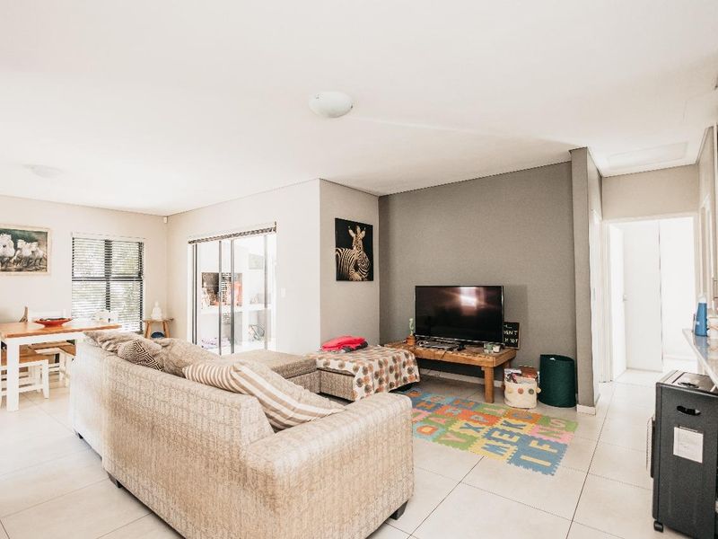 Open-plan living area featuring neutral tiled flooring, large sliding glass doors providing natural light, and a dedicated space for dining and lounge.