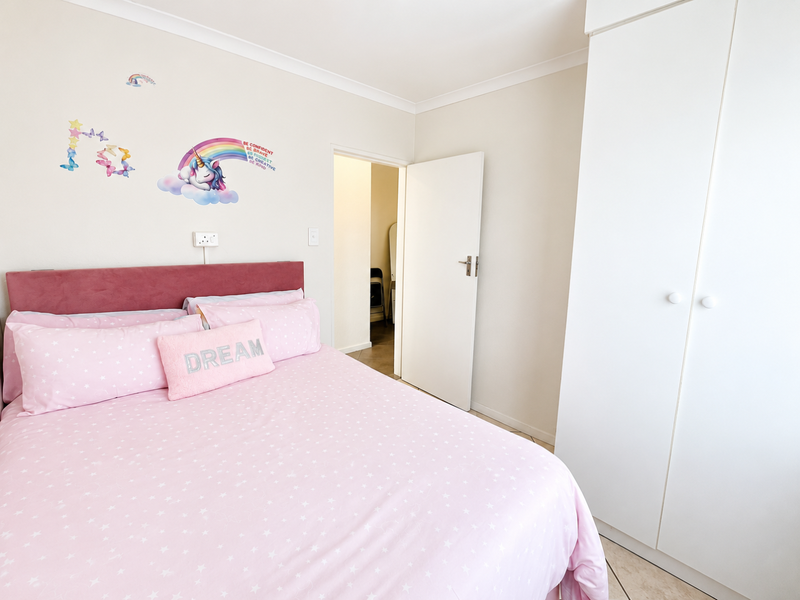 A well-maintained bedroom featuring neutral walls, tiled flooring, and a built-in wardrobe, offering a clean and functional living space.