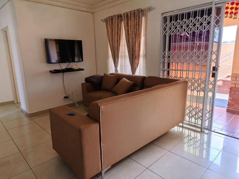 A living room featuring ceramic floor tiles, a sliding glass door with a security gate, and cove cornice detailing.