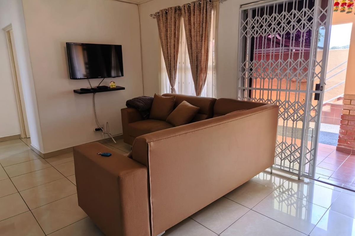 A living room featuring ceramic floor tiles, a sliding glass door with a security gate, and cove cornice detailing.