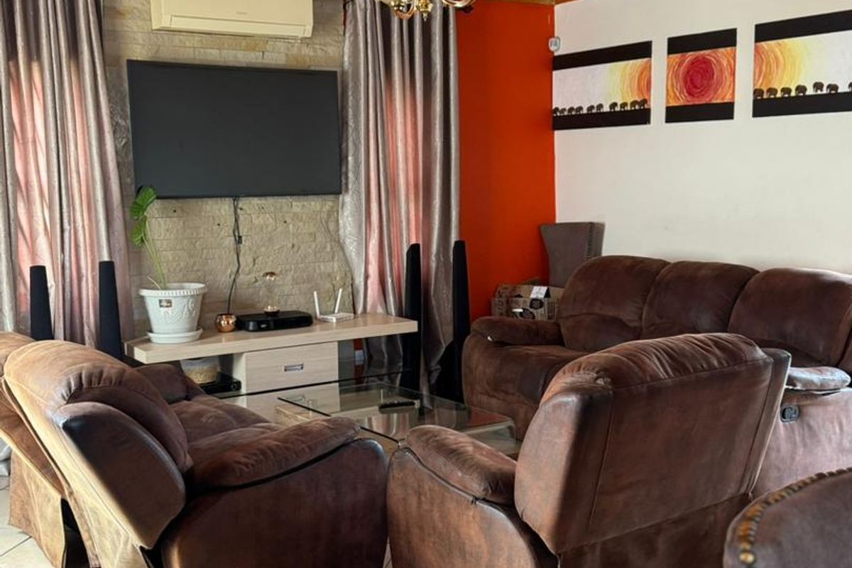 A living room featuring a wood-paneled ceiling, tiled flooring, and a stone-clad feature wall with a wall-mounted air conditioning unit.