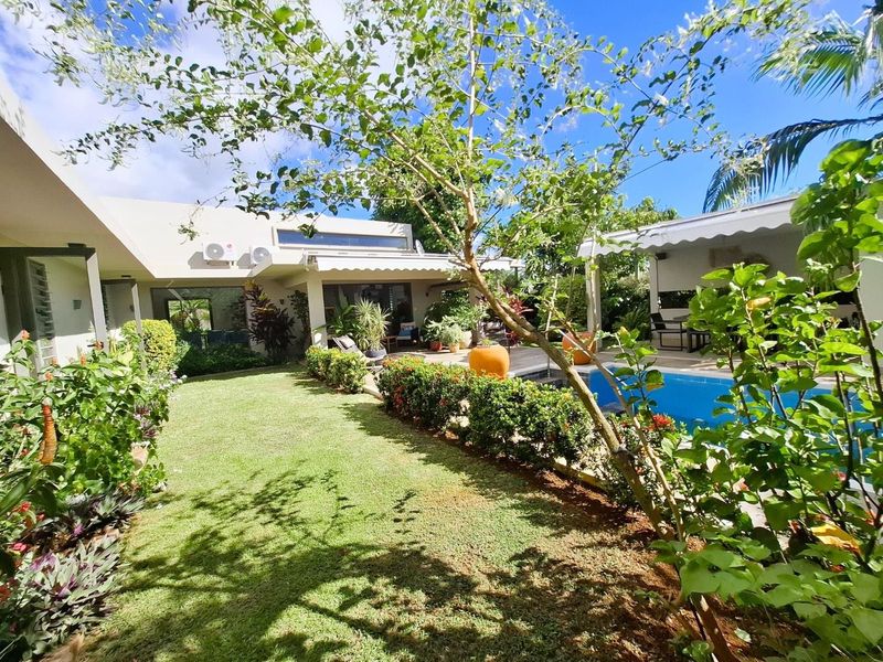 A well-maintained rear garden featuring a swimming pool, paved patio area, and retractable awning, providing an inviting outdoor entertainment space.