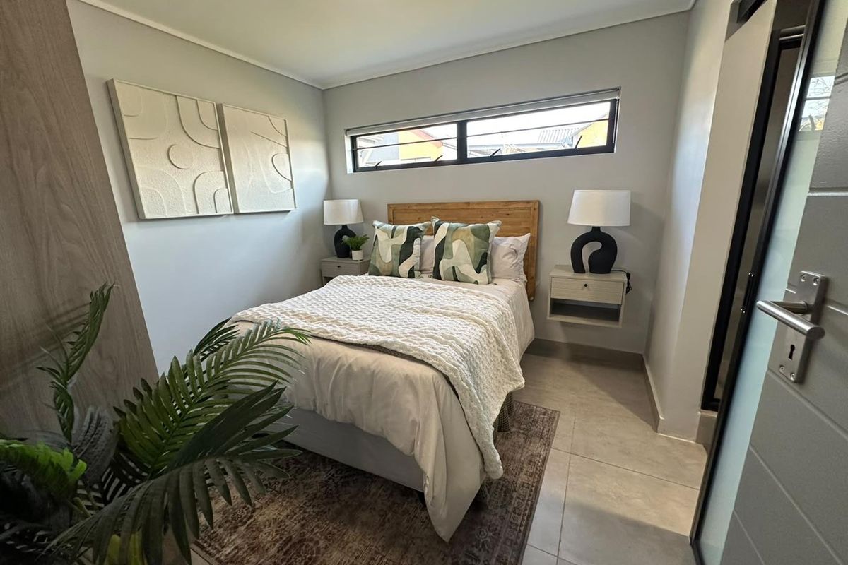 A modern, well-maintained bedroom featuring neutral tiled flooring, a horizontal clerestory window, and built-in storage solutions.