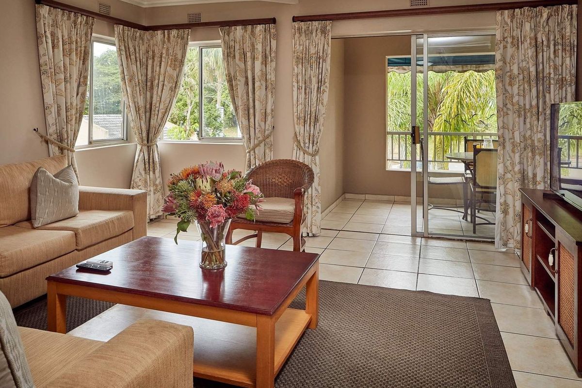 A comfortable living room featuring tiled flooring, large windows, and a sliding glass door that provides direct access to an outdoor patio area.