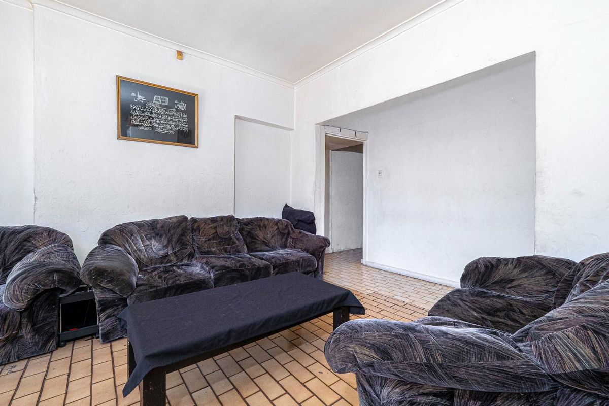 A living room featuring tiled flooring and coved ceilings, requiring cosmetic updates to improve the overall finish and aesthetic appeal.