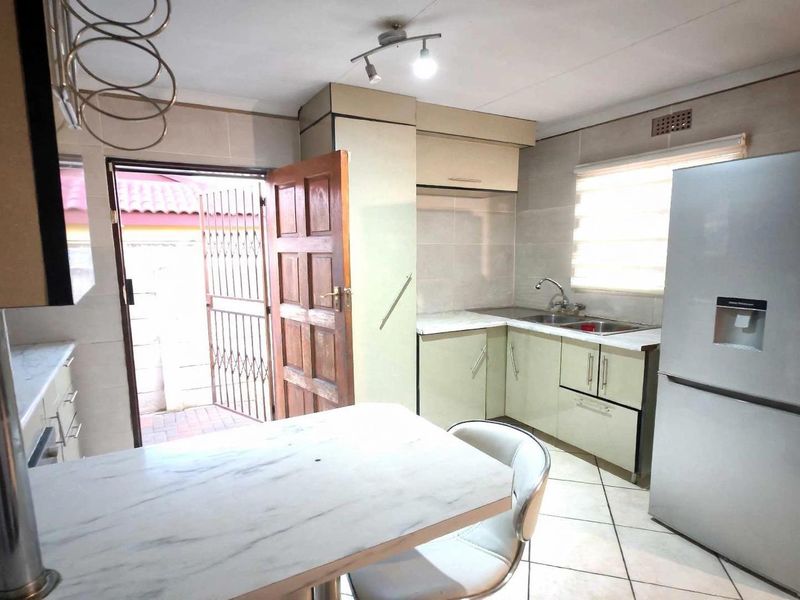Functional kitchen featuring built-in cabinetry, tiled surfaces, a breakfast bar, and direct access to the exterior.