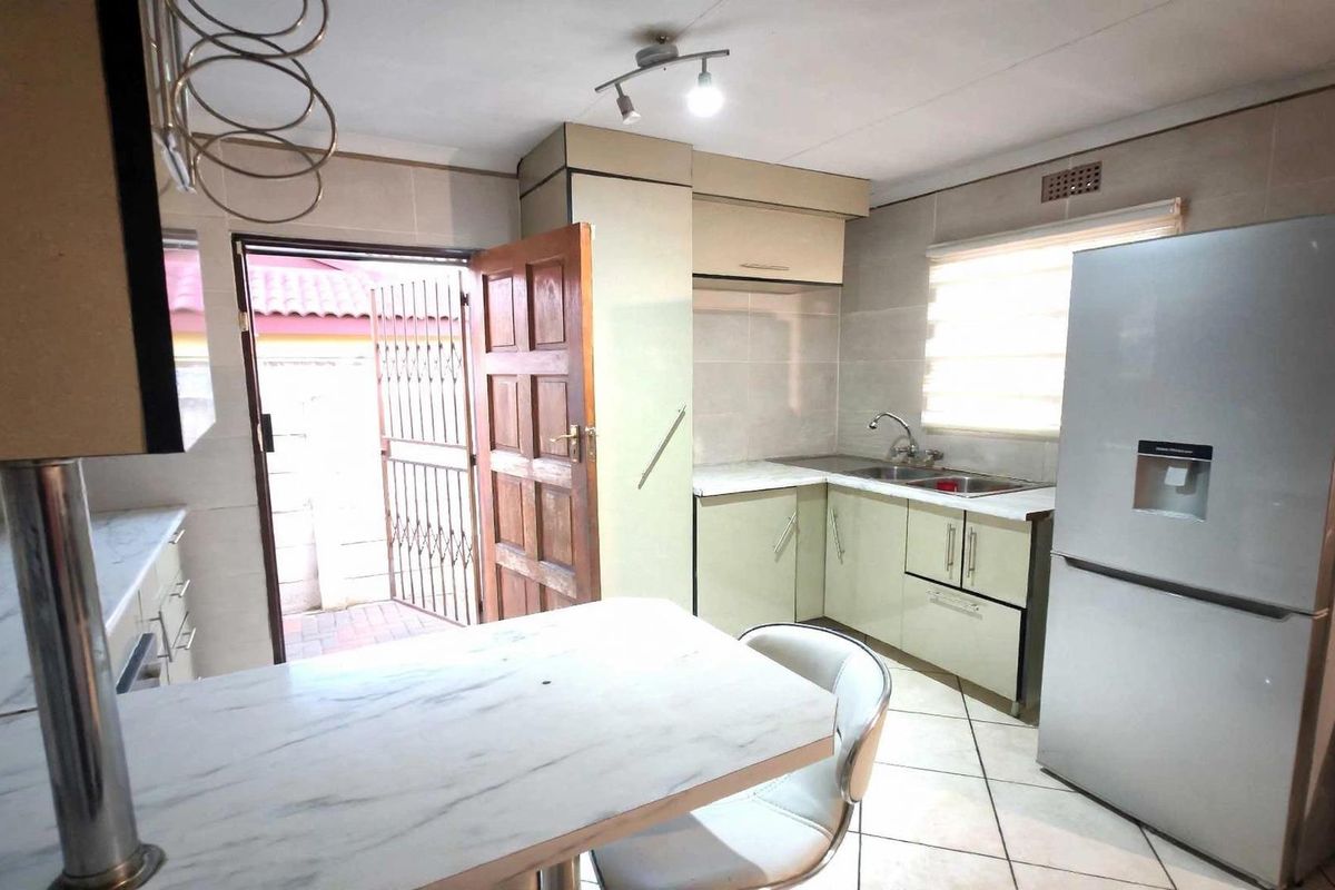 Functional kitchen featuring built-in cabinetry, tiled surfaces, a breakfast bar, and direct access to the exterior.