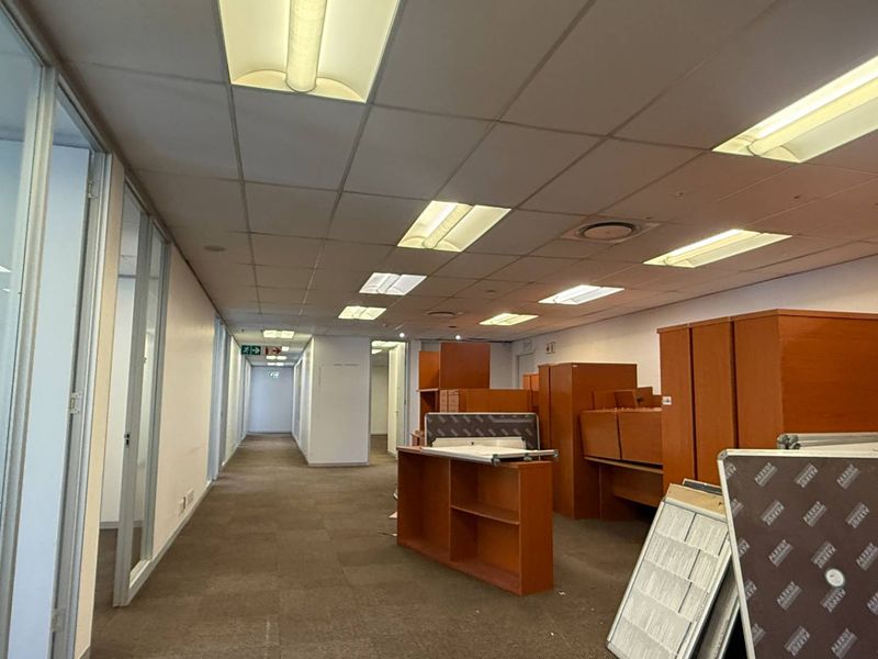 Open plan office space featuring glass partitions, suspended ceilings with integrated lighting, and carpeted flooring, suitable for a professional workspace.
