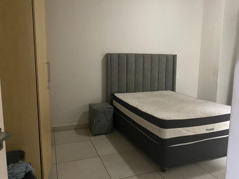 A bedroom featuring tiled flooring and a built-in wardrobe, providing a functional and neutral space.