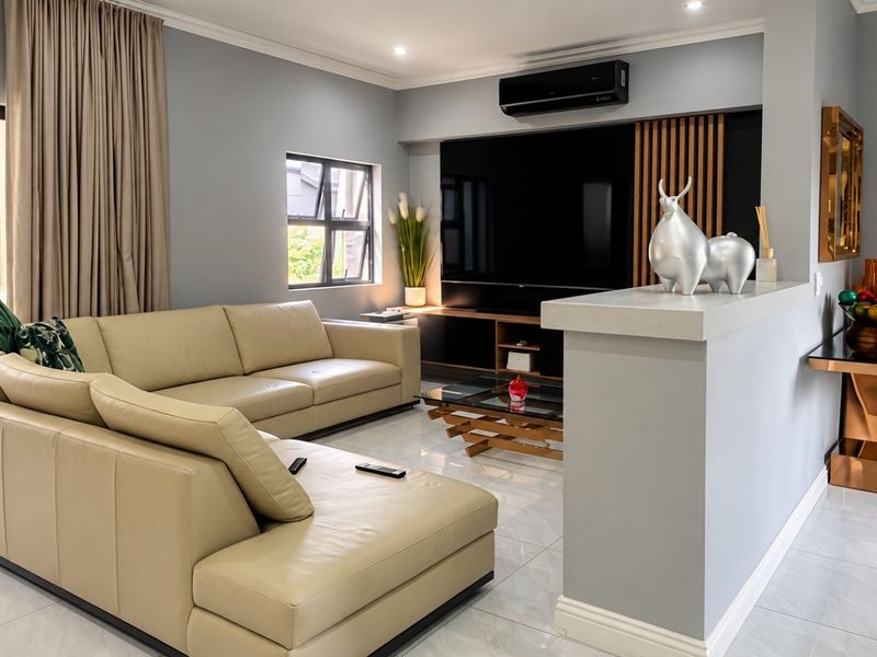 Modern living room featuring tiled flooring, a sleek built-in media wall with timber accents, and a wall-mounted air conditioning unit.