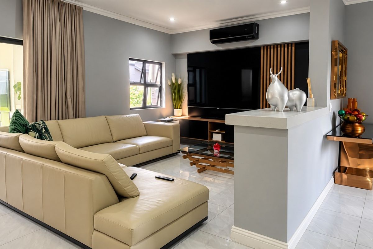 Modern living room featuring tiled flooring, a sleek built-in media wall with timber accents, and a wall-mounted air conditioning unit.