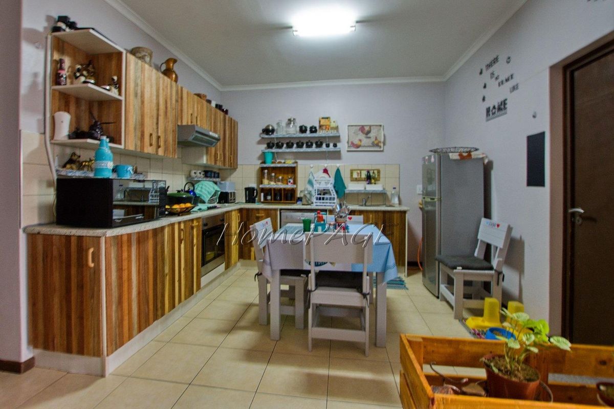 A functional kitchen featuring wood-finish cabinetry, tiled flooring, a built-in oven, and an extractor fan, providing a practical space for cooking and dining.