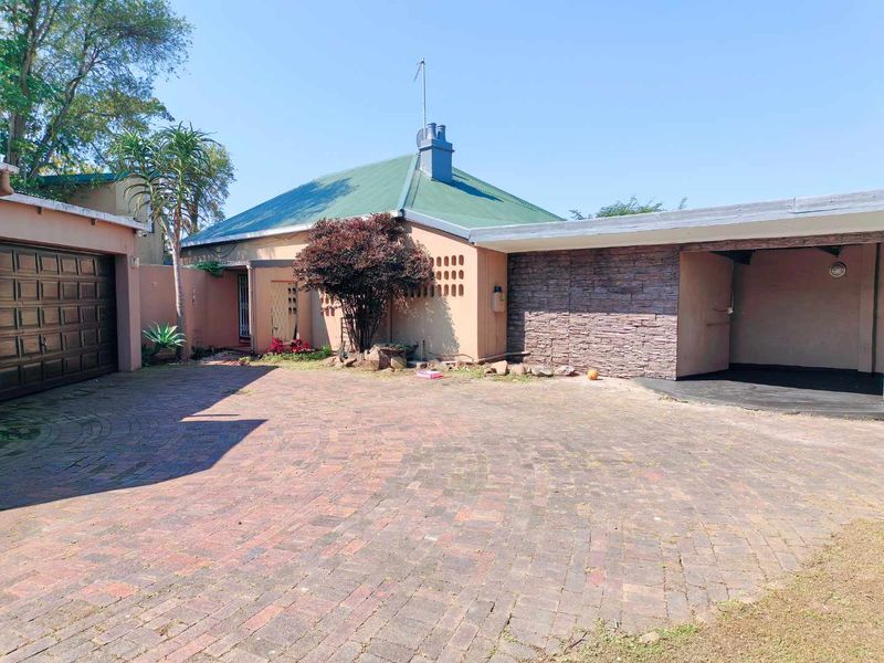 Front exterior view of the townhouse featuring a brick paved driveway, a single garage, and a covered carport area with stone cladding.