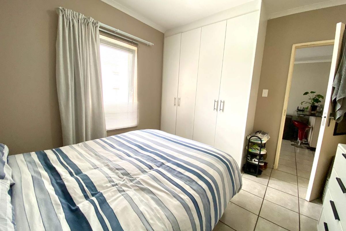 A functional bedroom featuring built-in cupboards, tiled flooring, and neutral wall tones, offering a clean and practical living space.