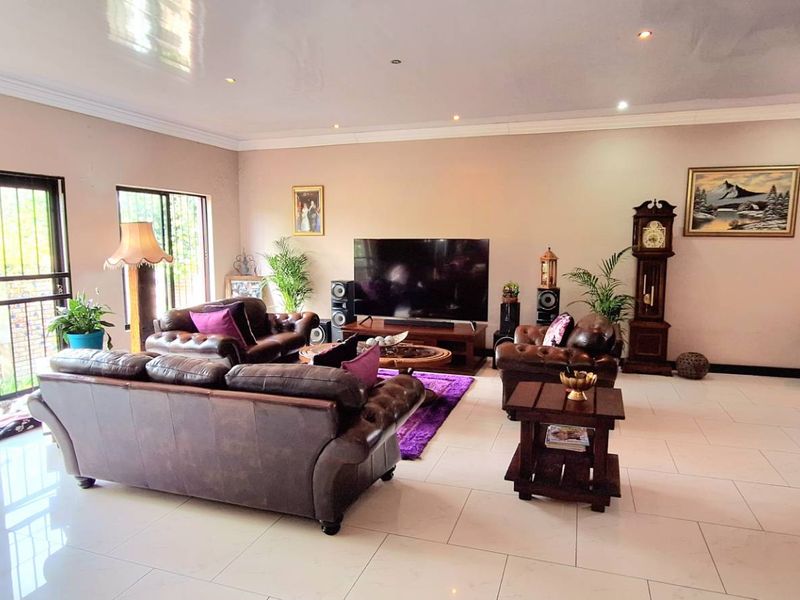 Spacious living room featuring large format floor tiles, recessed ceiling lighting, and expansive sliding glass doors with security bars.