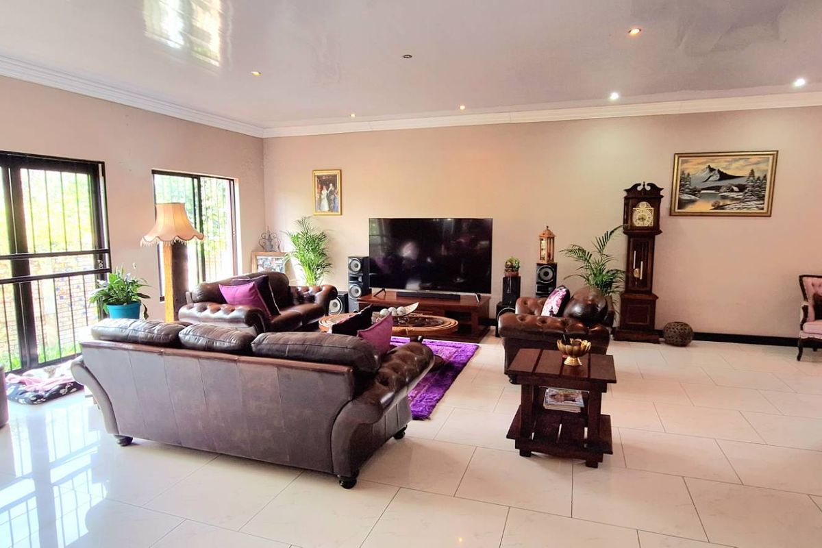 Spacious living room featuring large format floor tiles, recessed ceiling lighting, and expansive sliding glass doors with security bars.