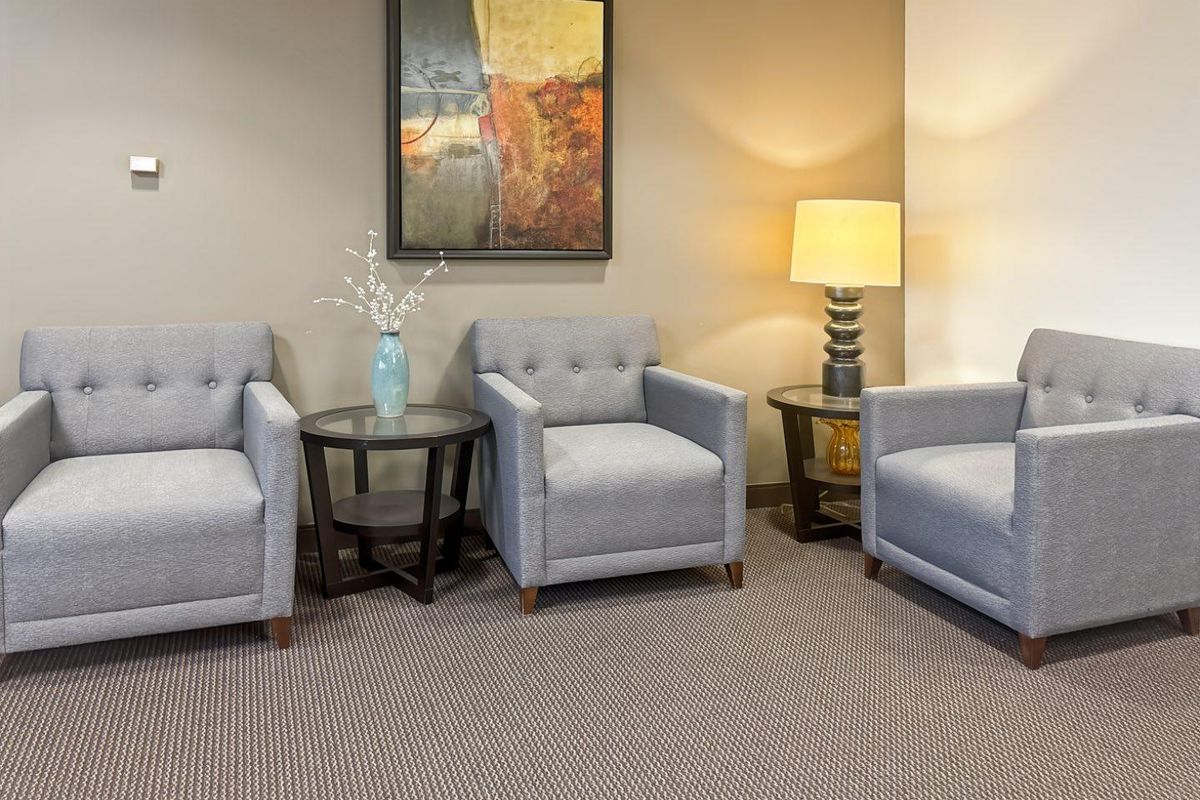 A professional office waiting area featuring neutral wall tones, carpeted flooring, and integrated lighting.