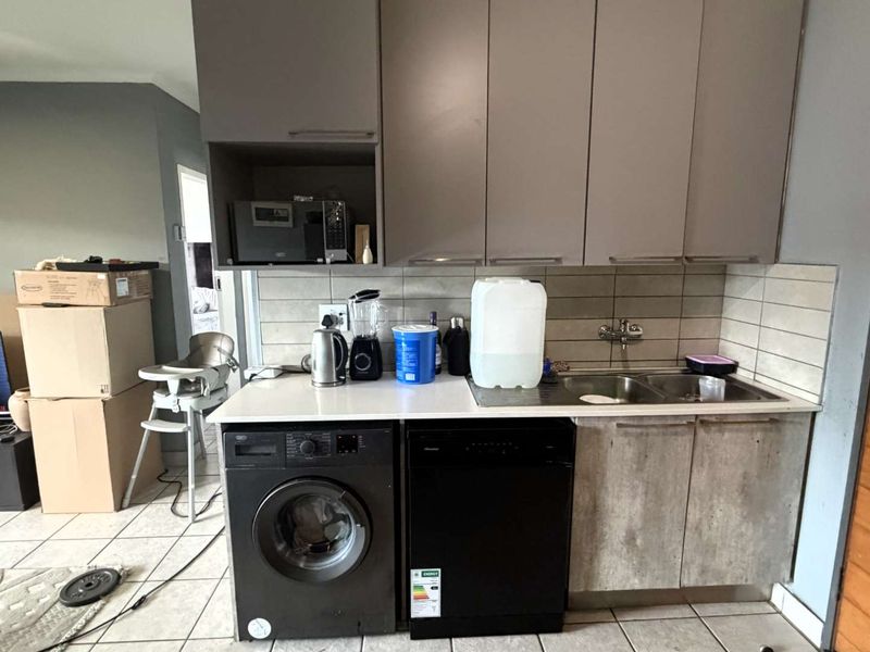 Compact kitchen area featuring built-in cabinetry, a double sink with mixer tap, tiled backsplash, and space for under-counter appliances.