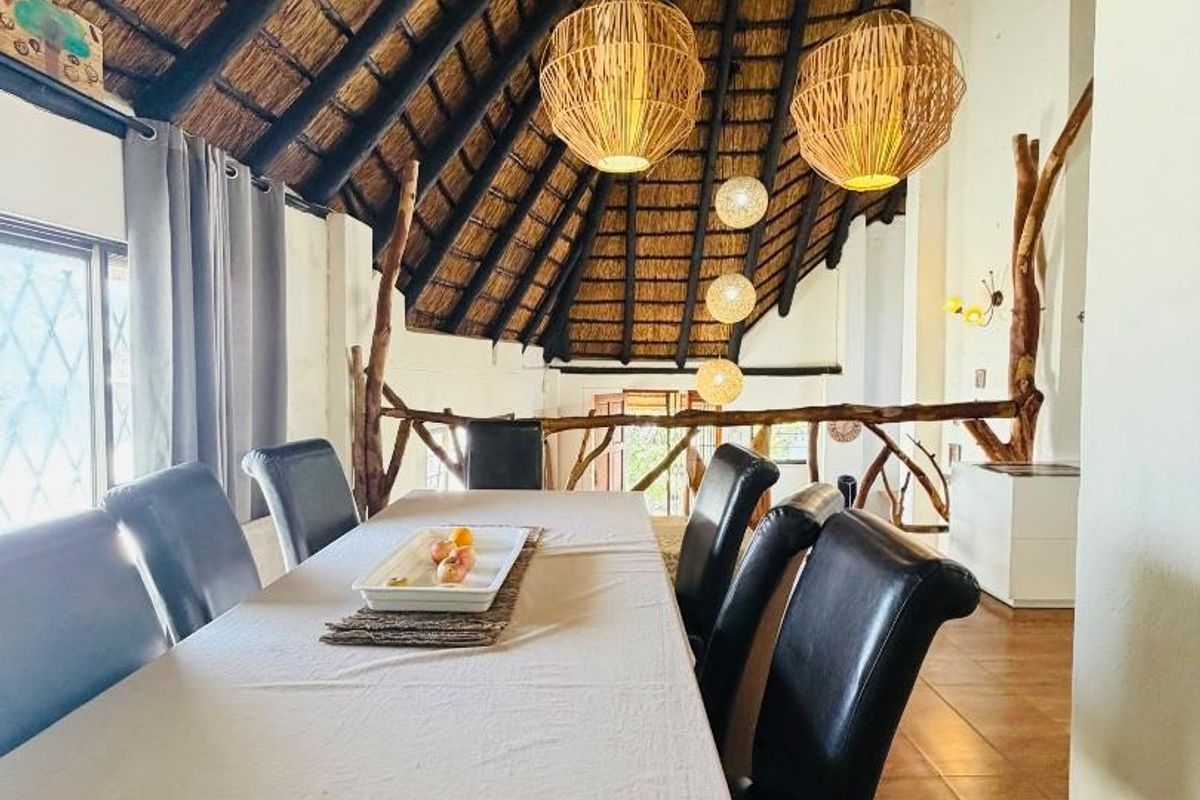 Dining area featuring a high vaulted thatched ceiling with exposed timber rafters and a rustic timber balustrade overlooking the lower level.