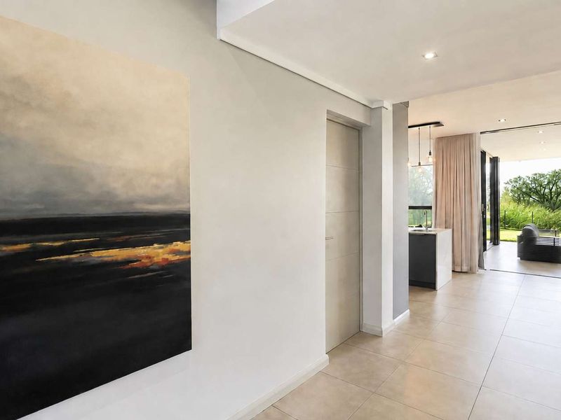 A bright open-plan living area featuring modern tiled flooring, recessed lighting, and seamless flow to an outdoor patio through large sliding glass doors.
