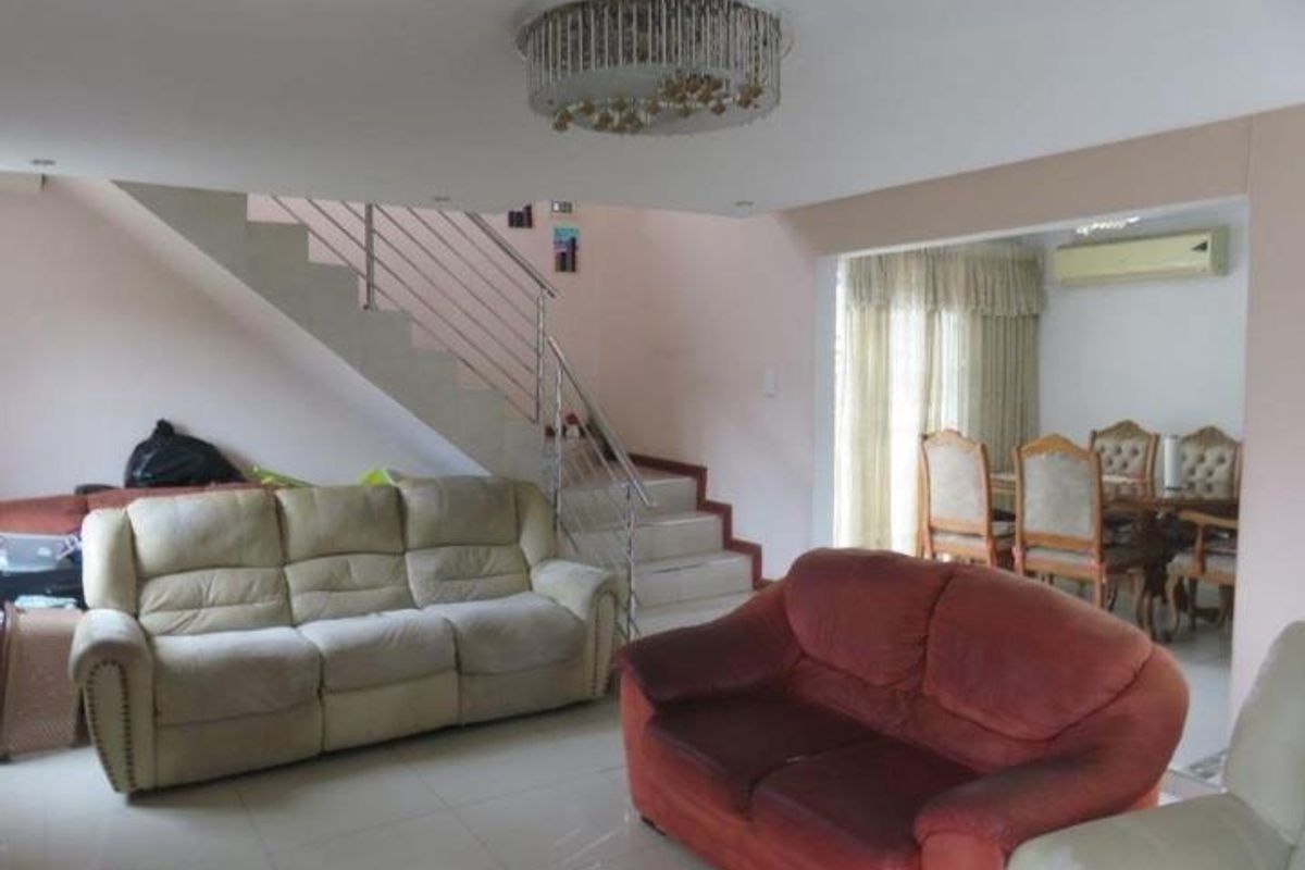 Open plan living and dining area featuring tiled flooring, a staircase with stainless steel balustrade, and a wall-mounted air conditioning unit.