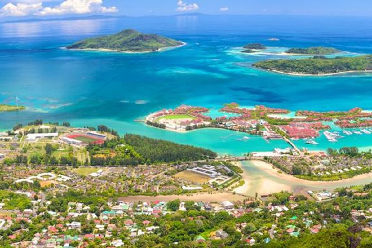 A panoramic aerial view showcasing the coastal landscape, surrounding islands, and turquoise waters of the Seychelles.