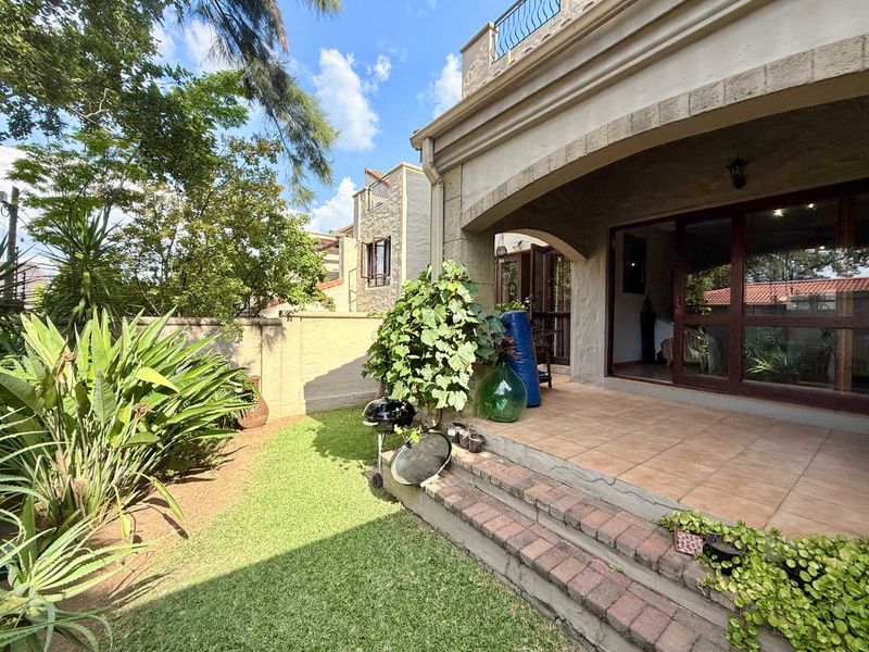 A ground-floor patio area with tiled flooring and brick steps, leading out to a private garden space with established greenery.