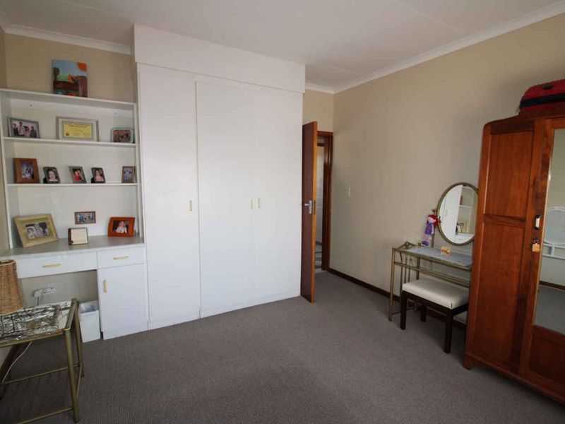 A bedroom featuring neutral walls, carpeted flooring, and a built-in wardrobe with integrated shelving for storage.