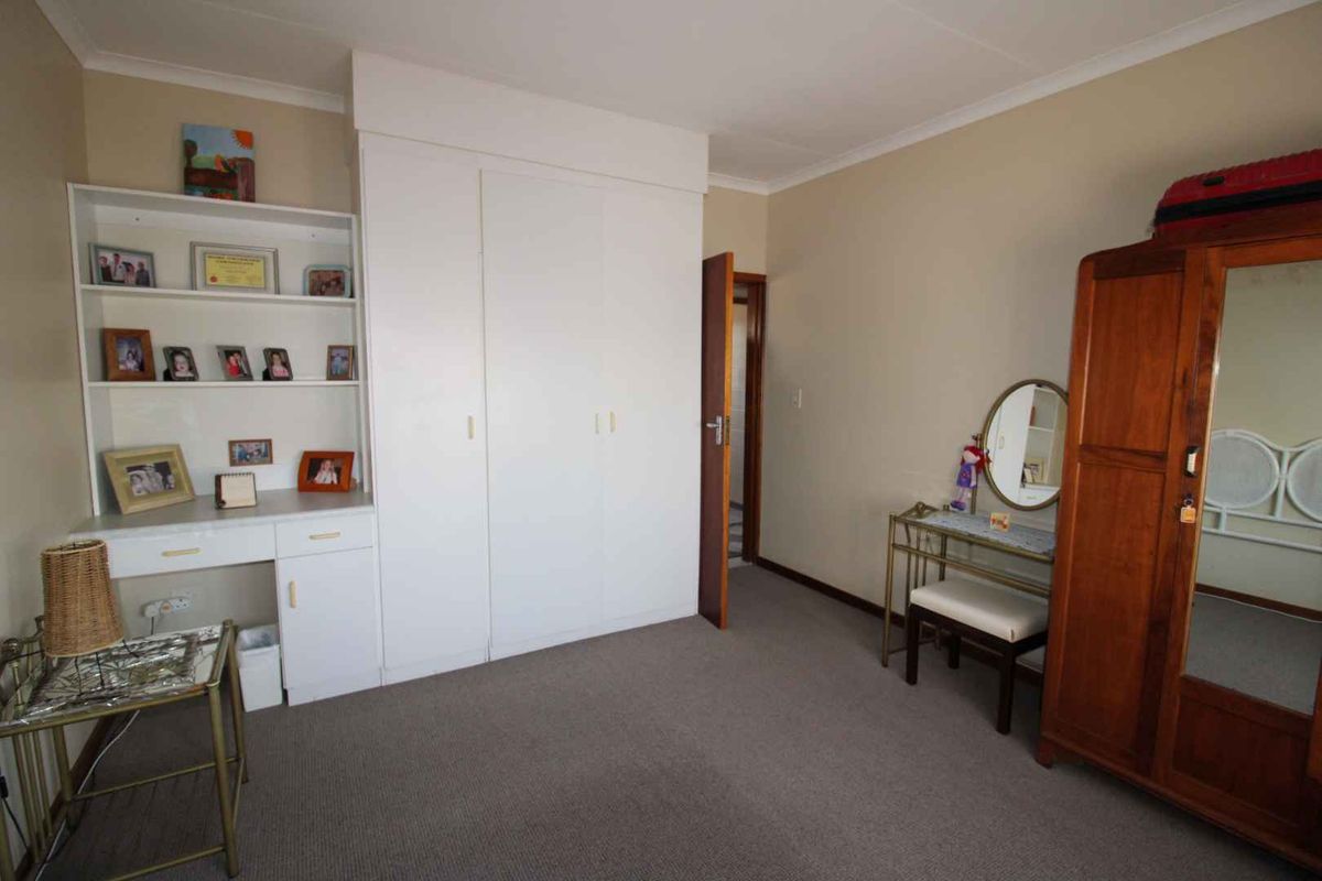 A bedroom featuring neutral walls, carpeted flooring, and a built-in wardrobe with integrated shelving for storage.