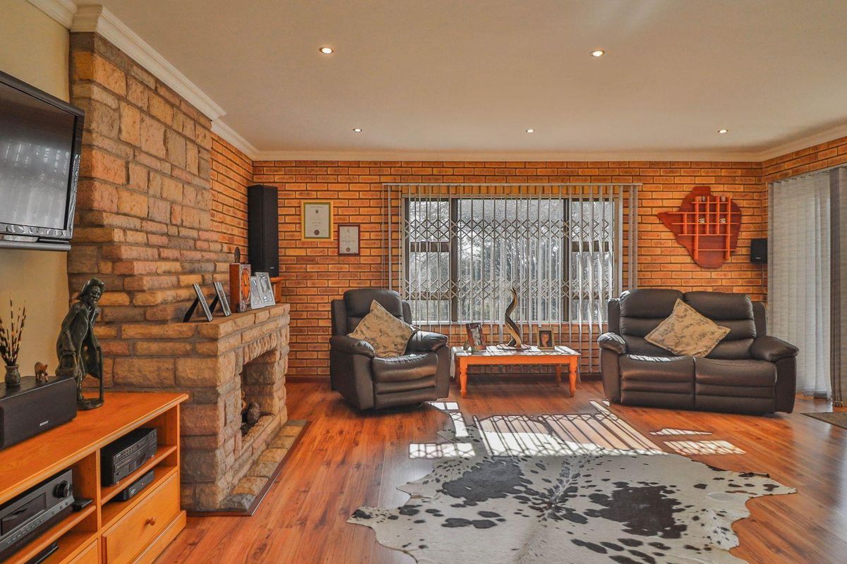 Spacious living room featuring exposed brick walls, a stone-clad fireplace, recessed ceiling lighting, and sliding glass doors leading to the outdoor area.
