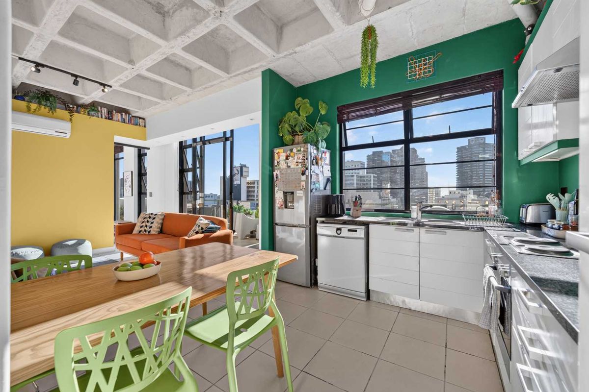 Open-plan living and kitchen area featuring a distinctive waffle slab concrete ceiling, modern cabinetry, and large windows with urban views.