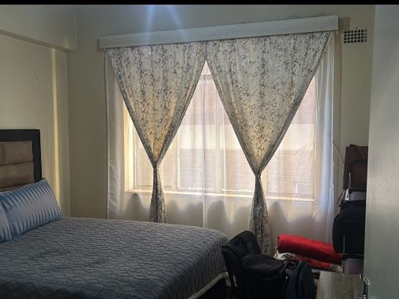A standard bedroom featuring a large window with built-in ventilation, providing natural light and a functional layout.