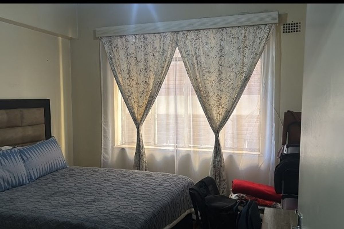 A standard bedroom featuring a large window with built-in ventilation, providing natural light and a functional layout.