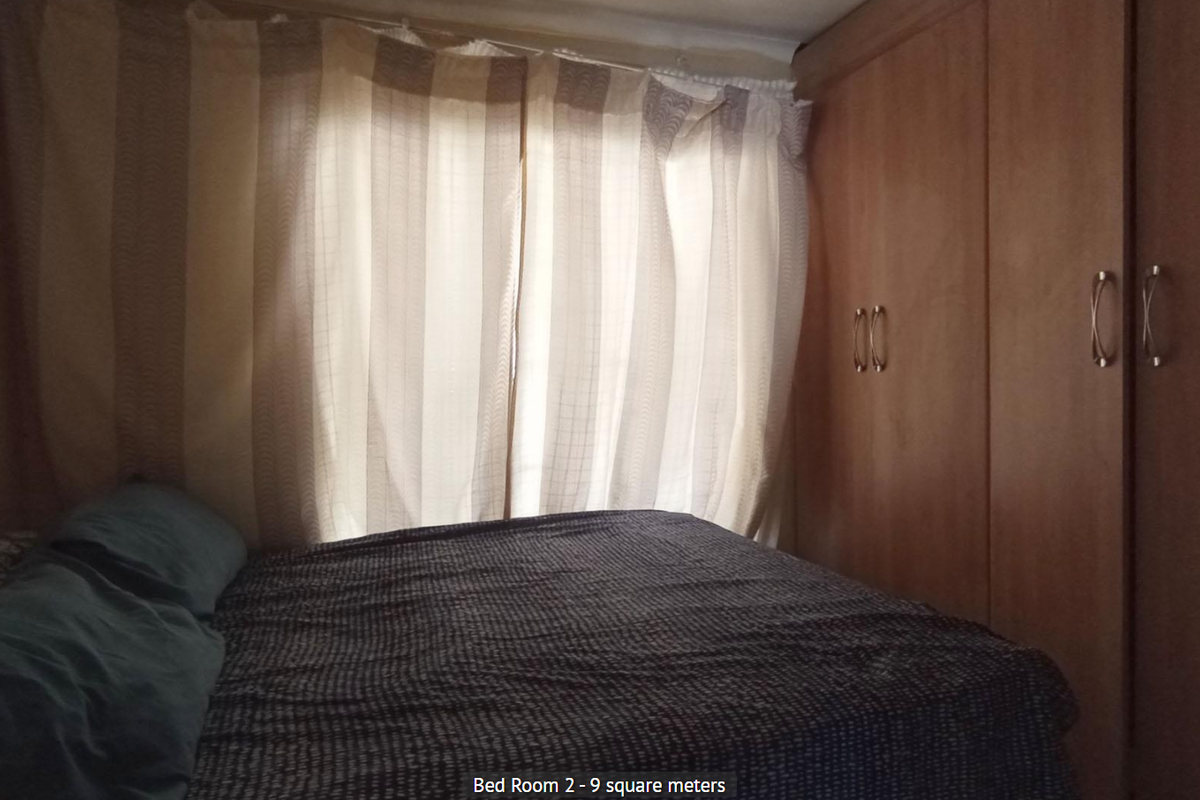 A compact bedroom featuring built-in wooden cabinetry and window curtains.
