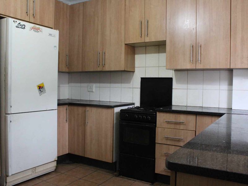 Functional kitchen featuring light wood-look cabinetry, dark granite countertops, and a tiled backsplash, providing a practical workspace with standard fixed appliances.
