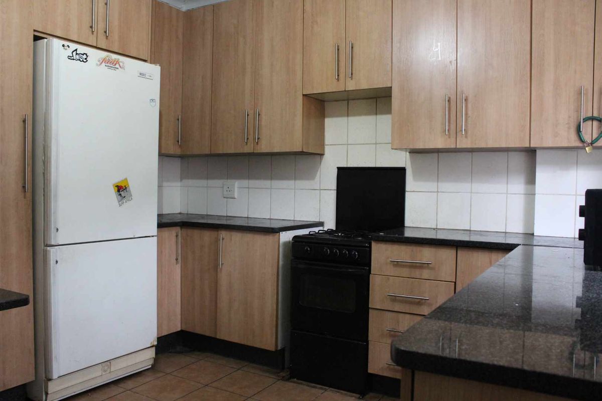 Functional kitchen featuring light wood-look cabinetry, dark granite countertops, and a tiled backsplash, providing a practical workspace with standard fixed appliances.