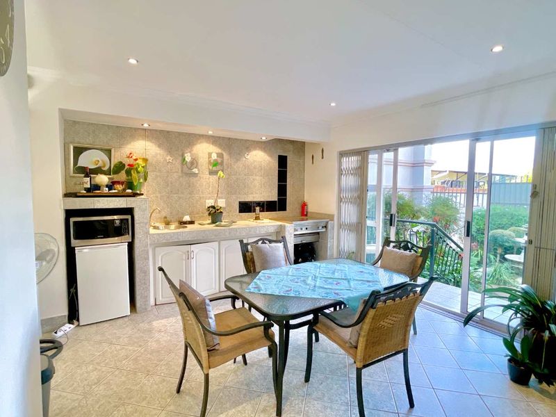 A functional kitchen area featuring tiled finishes, built-in cabinetry, and direct access to an outdoor patio through sliding glass doors.