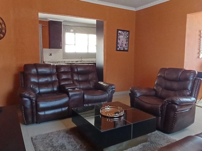 Open plan living area featuring tiled flooring and coving, with a view through to the adjacent kitchen space.