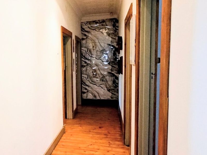 A bright hallway featuring polished timber flooring, classic timber door frames, and a decorative ceiling, providing access to multiple rooms.