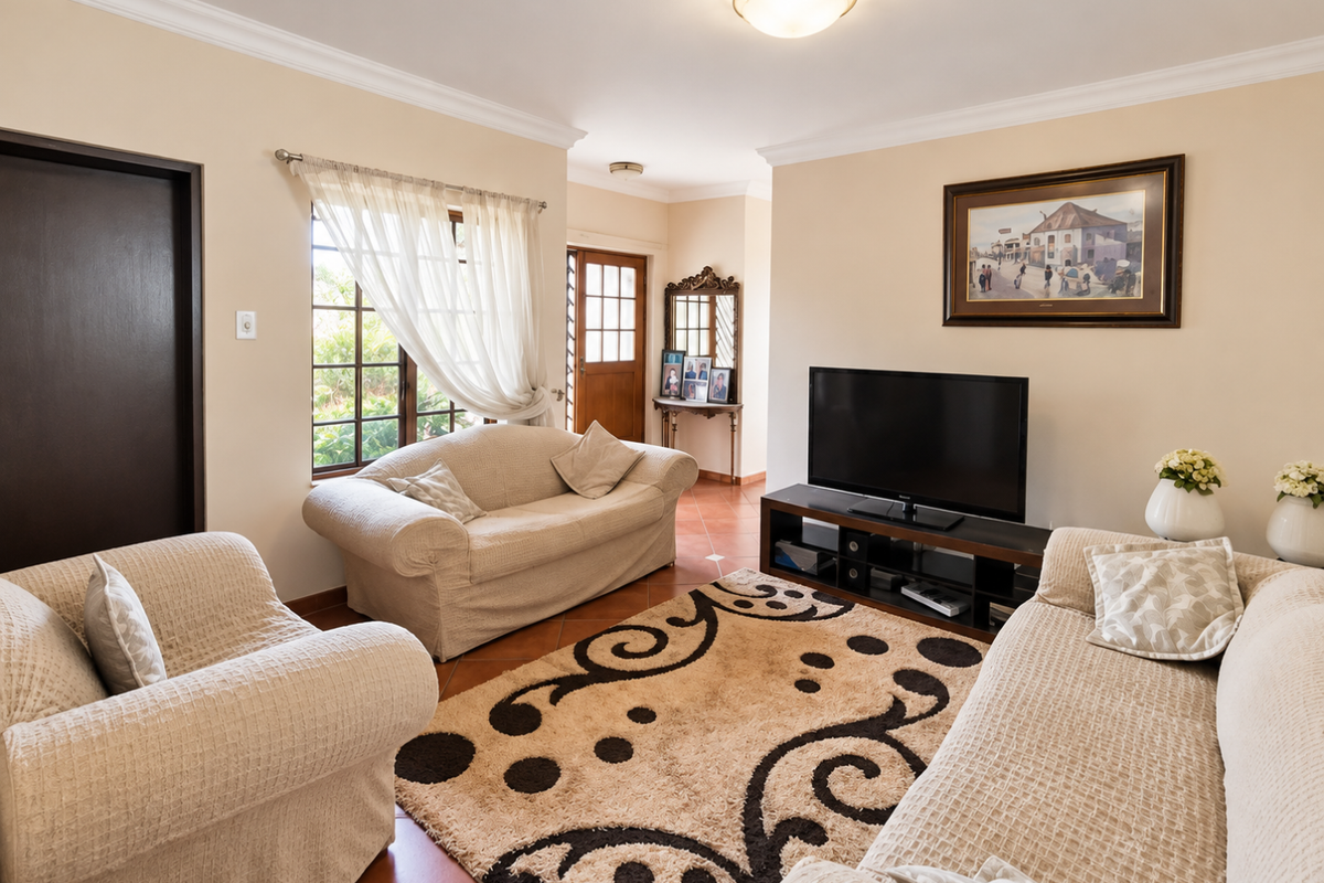 A comfortable living room featuring tiled flooring, neutral walls, and natural light through timber-framed windows, providing a warm and inviting atmosphere.
