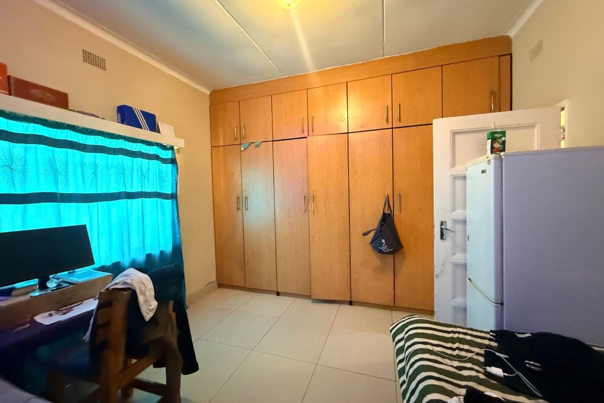 A bedroom featuring extensive built-in wooden cabinetry, tiled flooring, and a standard panel door.
