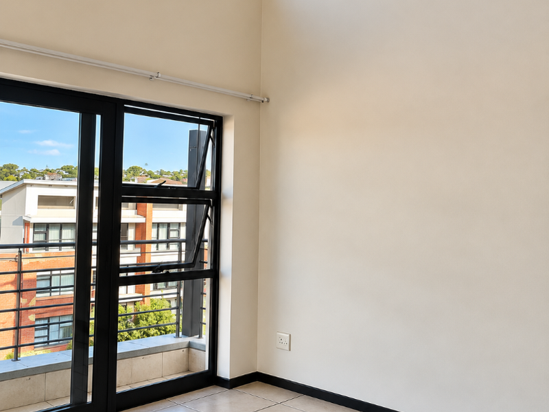 Bright and spacious living area featuring high ceilings, large black aluminium windows, and neutral tiled flooring with access to a private balcony.