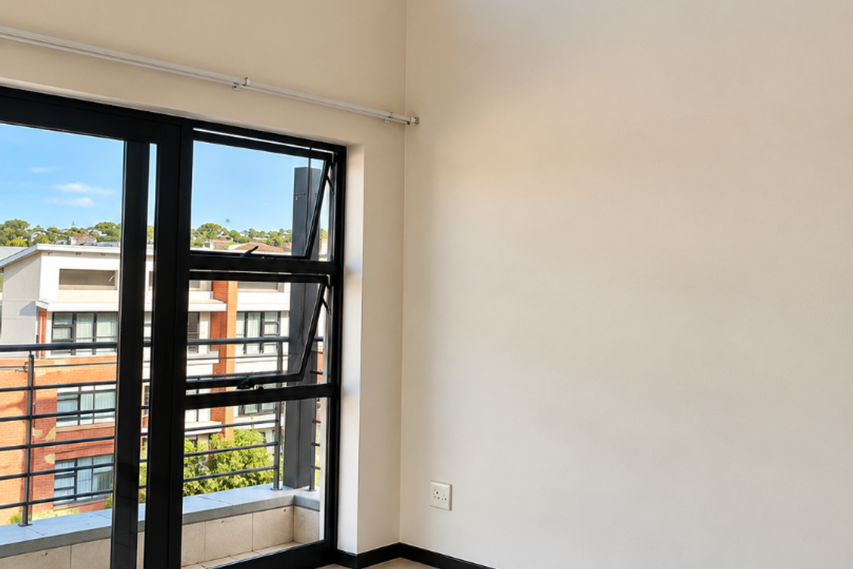 Bright and spacious living area featuring high ceilings, large black aluminium windows, and neutral tiled flooring with access to a private balcony.